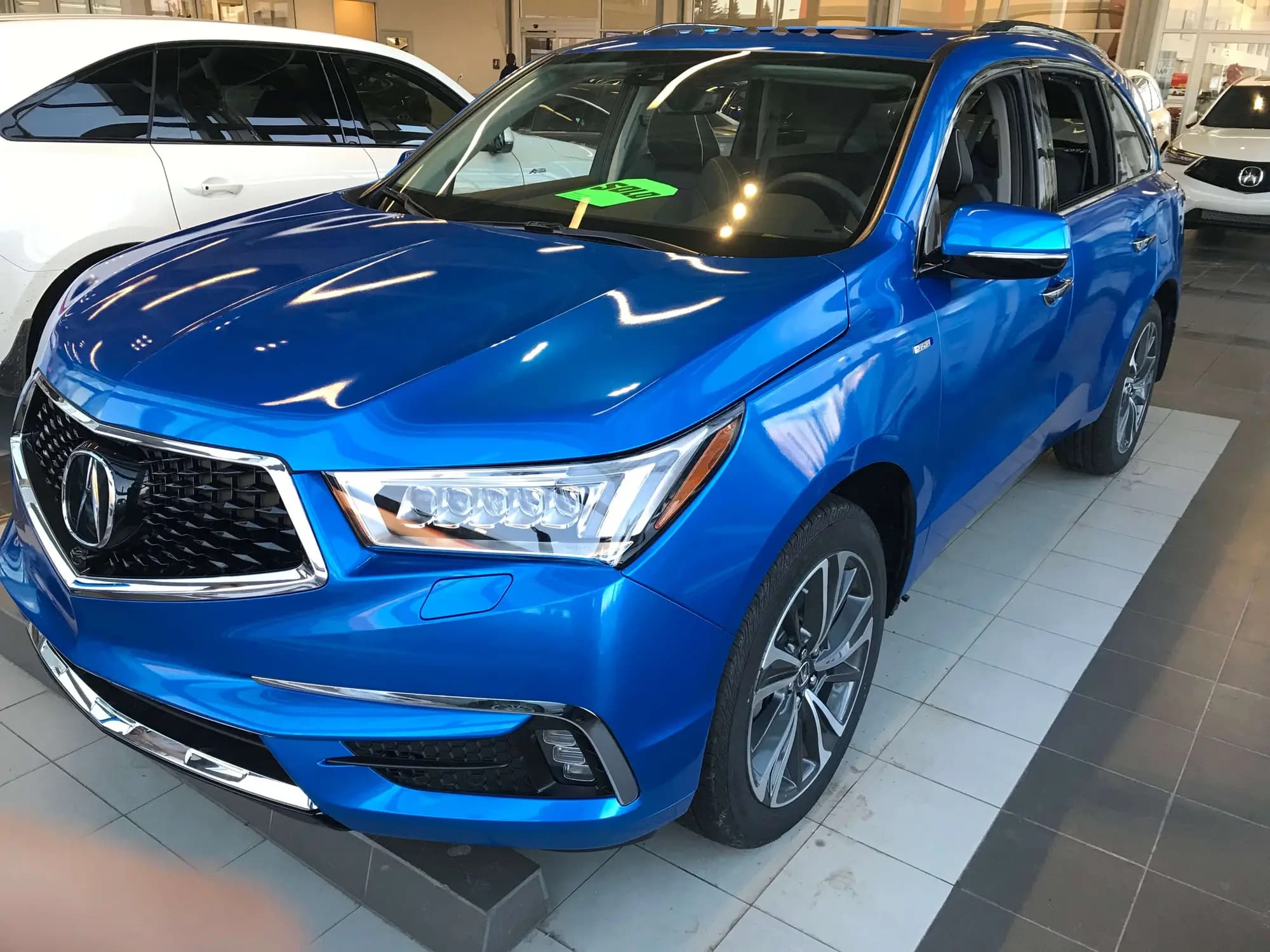Acura MDX wrapped in Gloss Blue Fire, parked indoors on a showroom floor