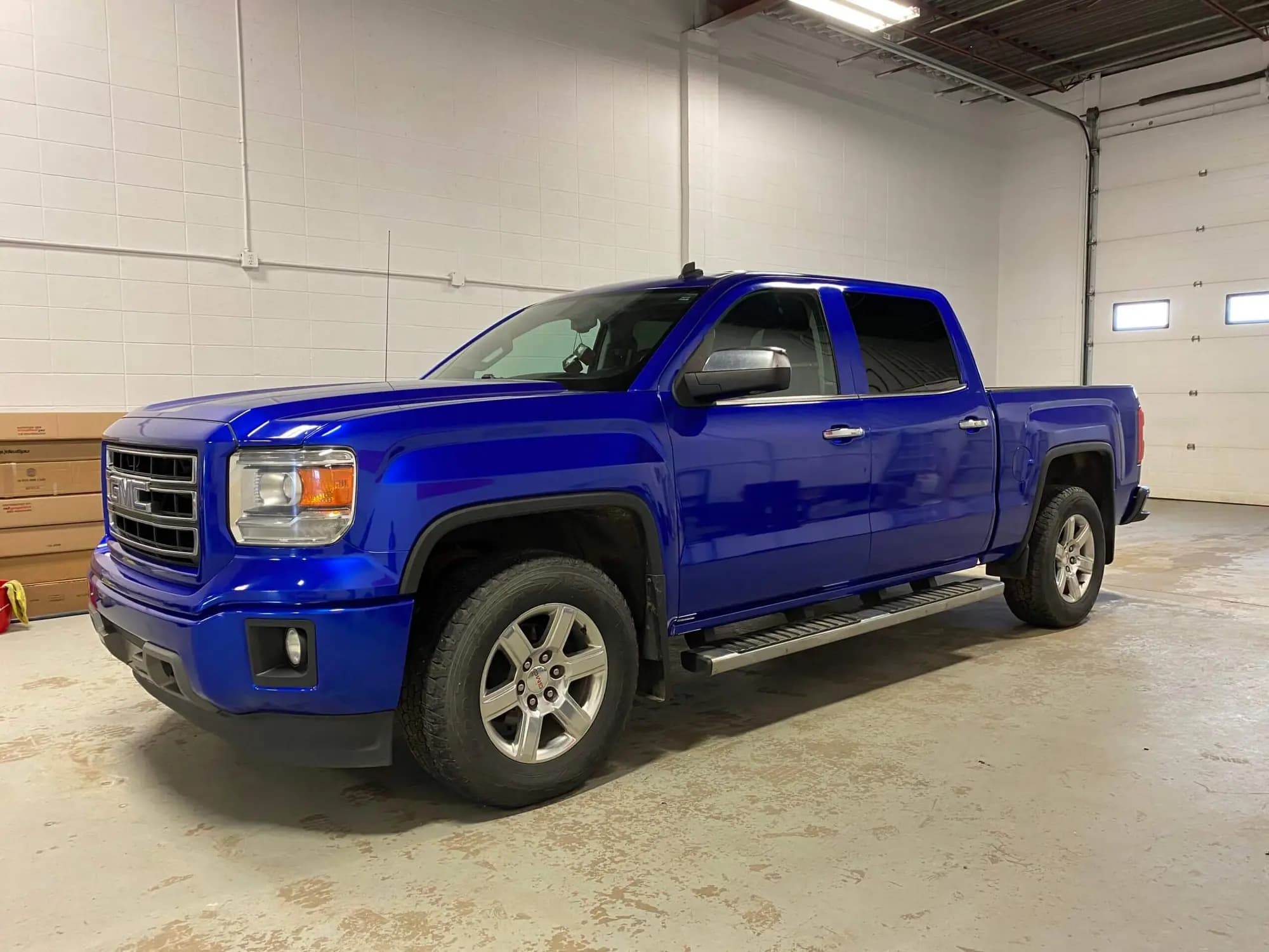 GMC crew cab pickup wrapped in Gloss Cosmic Blue, parked inside a shop bay